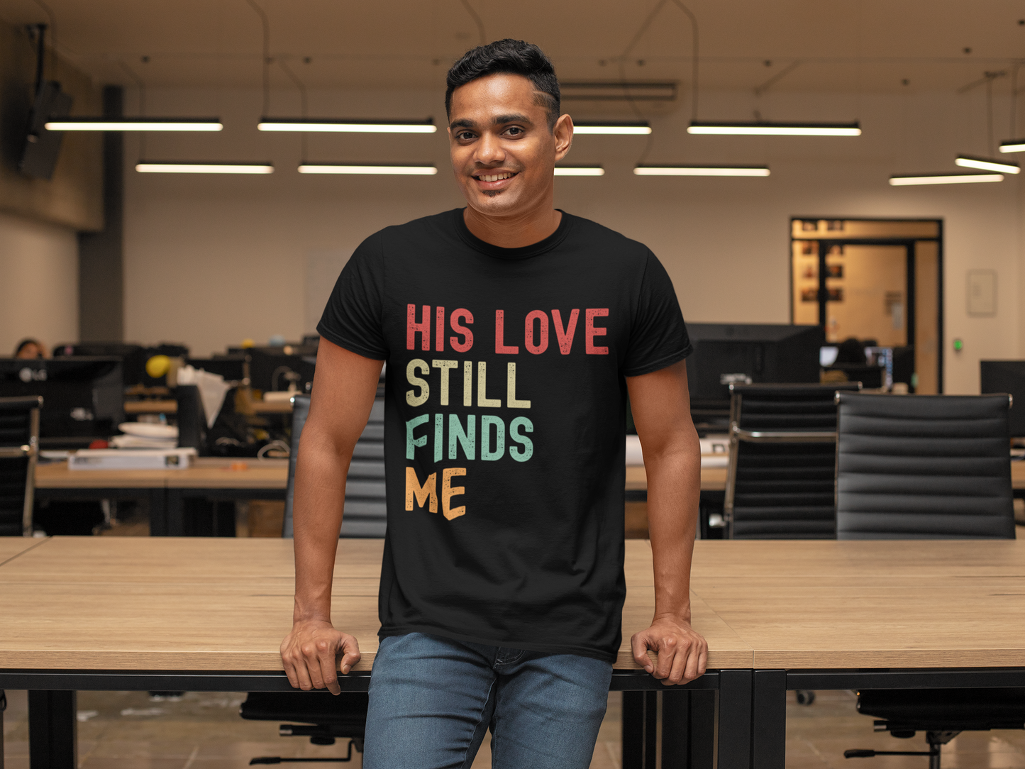 Man wearing a black t-shirt with colorful text in an office setting
