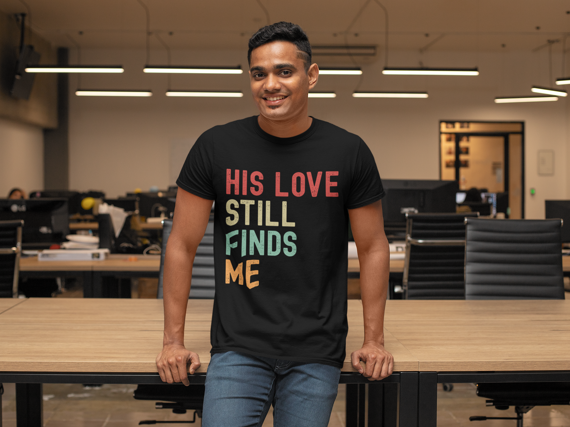 Man wearing a black t-shirt with colorful text in an office setting